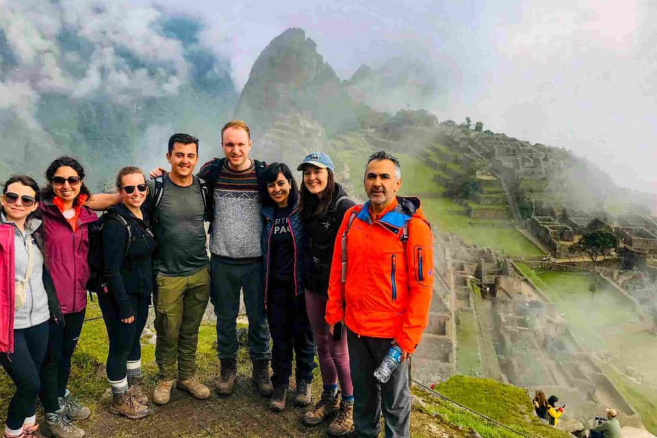 Turistas reunidos en los andenes superiores de Machu Picchu, de fondo la ciudadela - Valle Sagrado y Camino Inca Corto