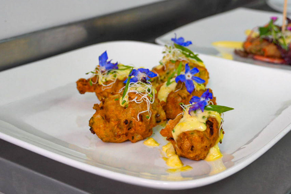 Plato de comida servido con una porción central decorada y varios acompañamientos sobre una bandeja blanca | TreXperience