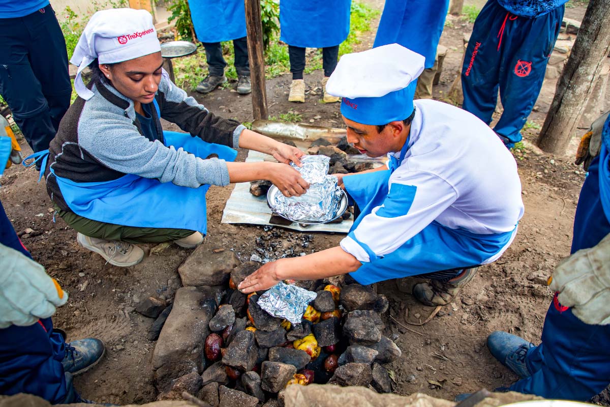 Personas preparando comida peruana al aire libre durante una caminata en Cusco | TreXperience 