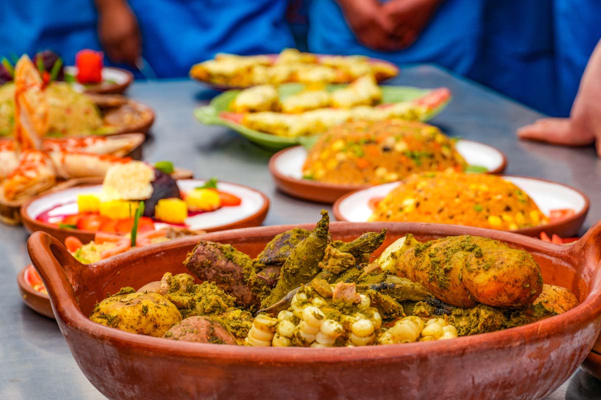 Varios platos de comida peruana servida sobre una mesa, con una fuente grande de vegetales y acompañamientos coloridos | TreXperience