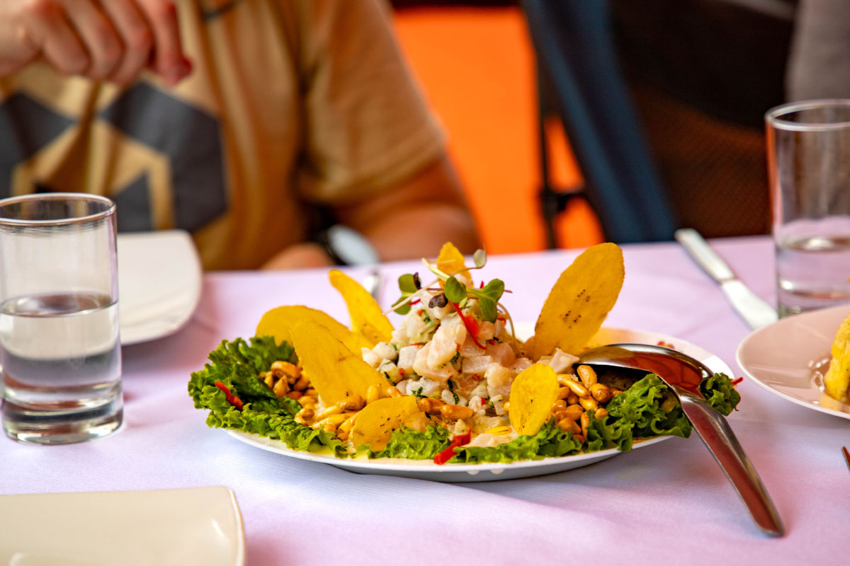 Ceviche served on a white table, with a decorated central portion and colorful accompaniments.