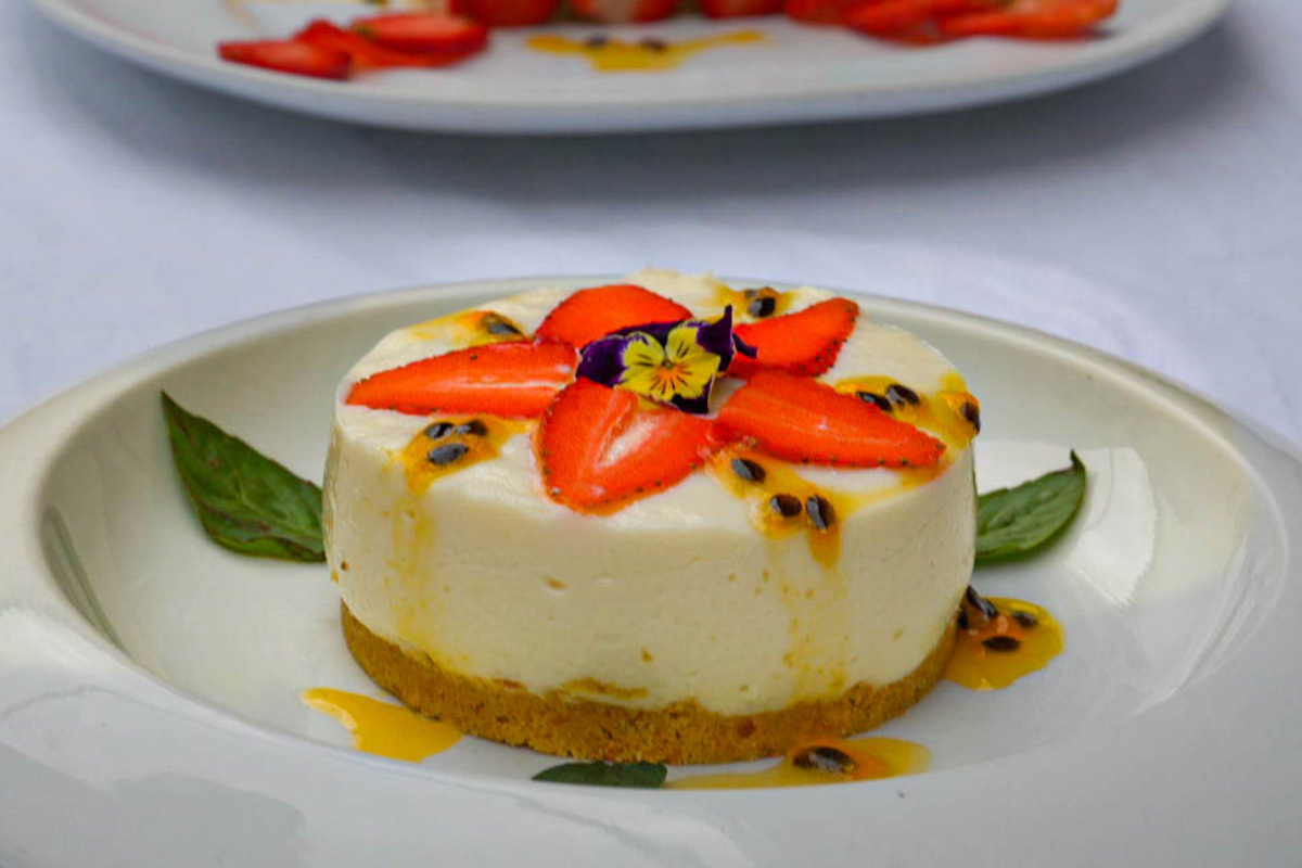 Postre decorado y con acompañamientos verdes y rojos sobre un plato blanco | TreXperience