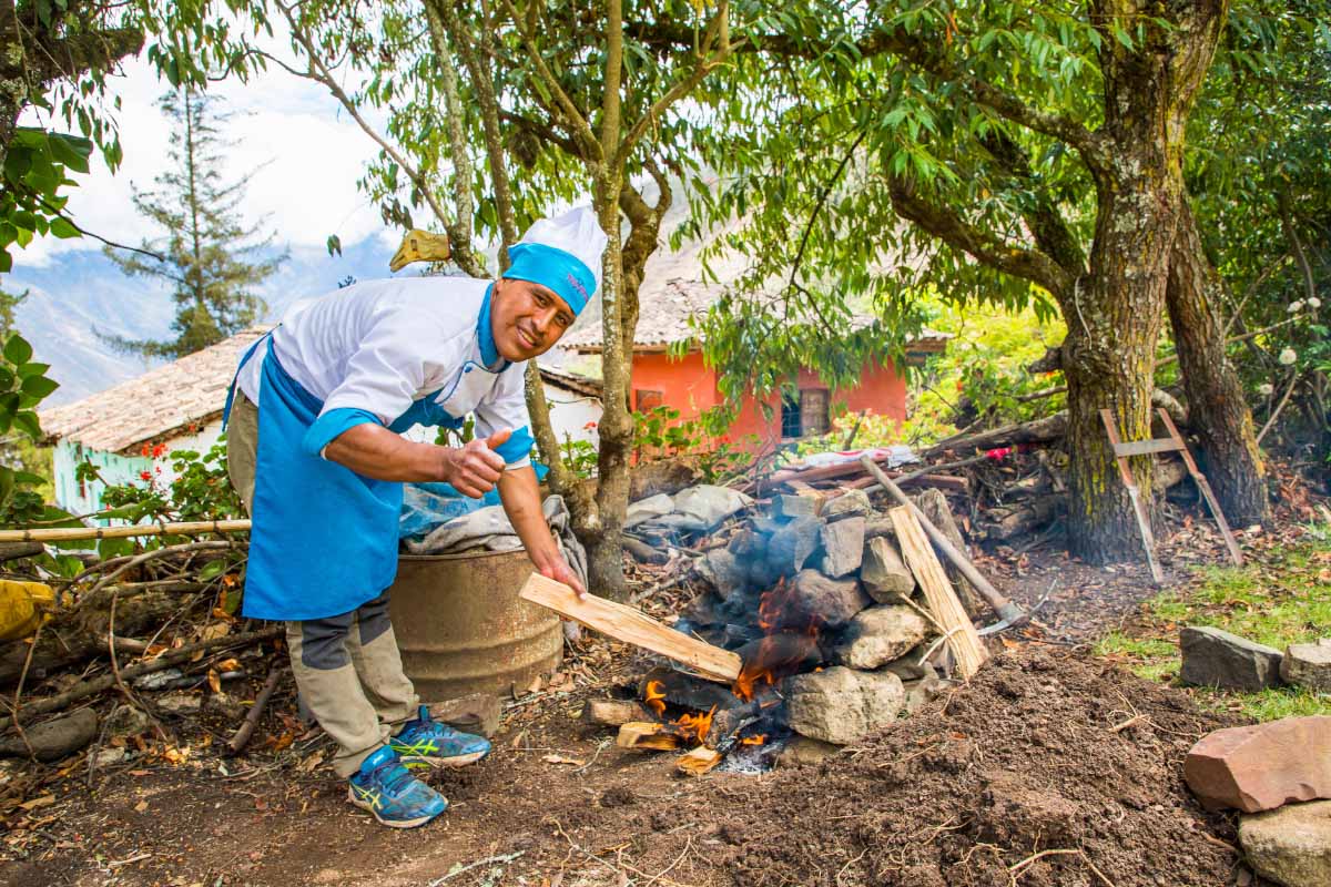 Chefs de TreXpereince con uniforme azul preparando alimentos al aire libre, rodeadas de árboles y utensilios de cocina | TreXperience