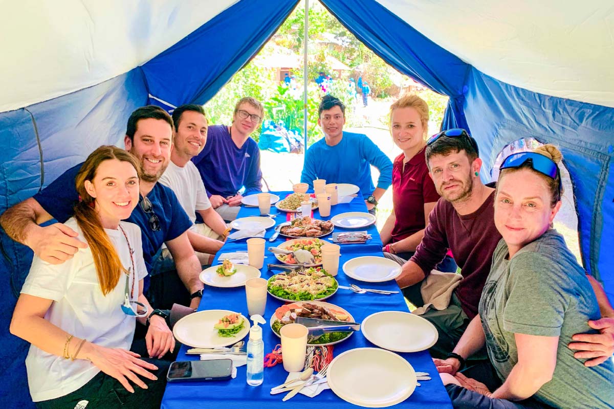 Group of travelers sitting around a table with food and drinks under a colorful tent | TreXperience