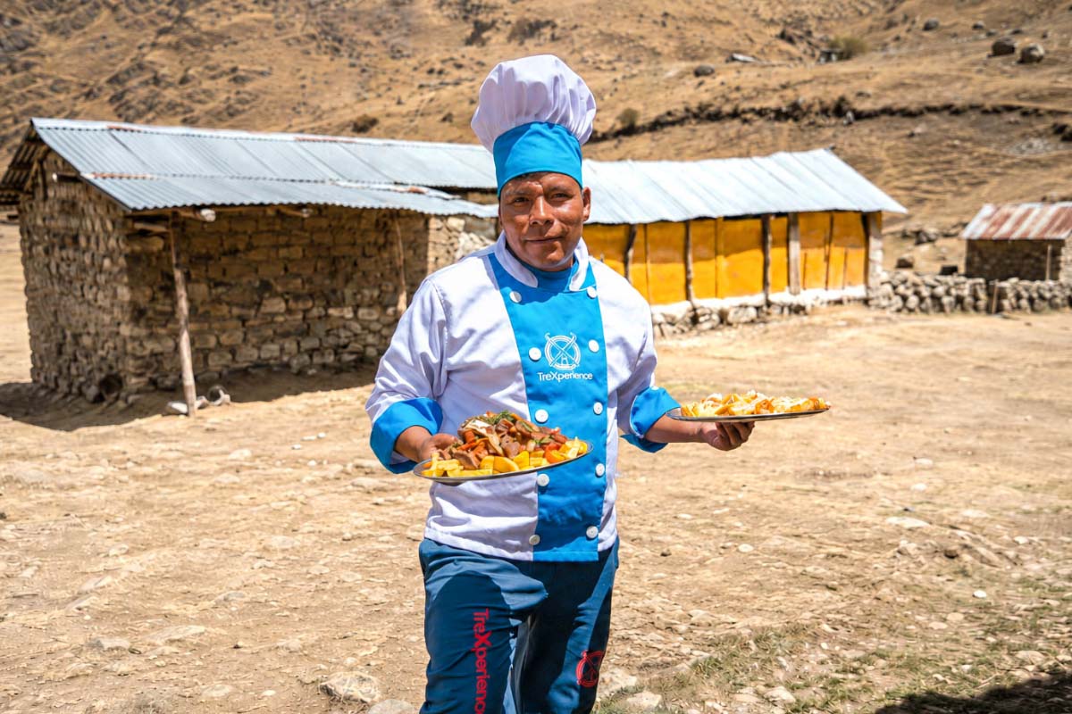 TreXperience chef in blue uniform holding a plate of food outdoors | TreXperience
