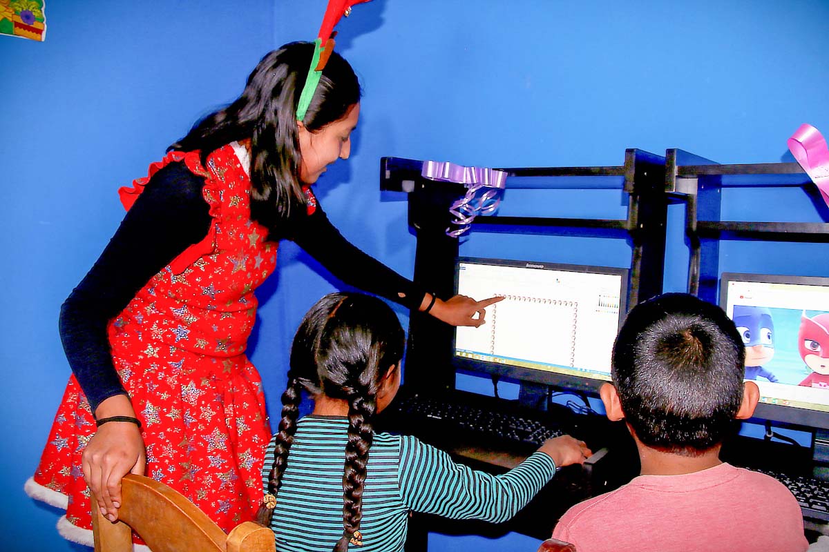 Teacher teaching computer skills to Cachicata children | TreXperience
