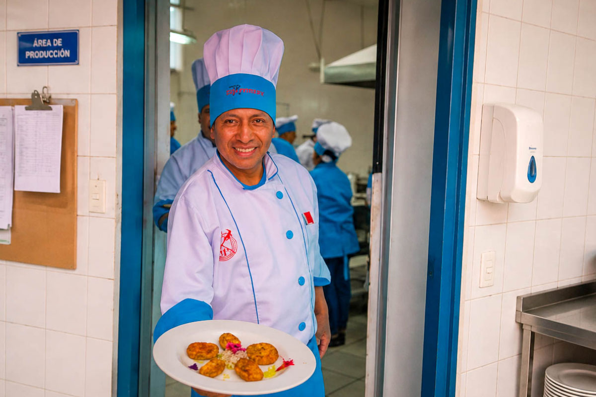 Cocinero de TreXperience con uniforme claro sosteniendo un plato con comida | TreXperience