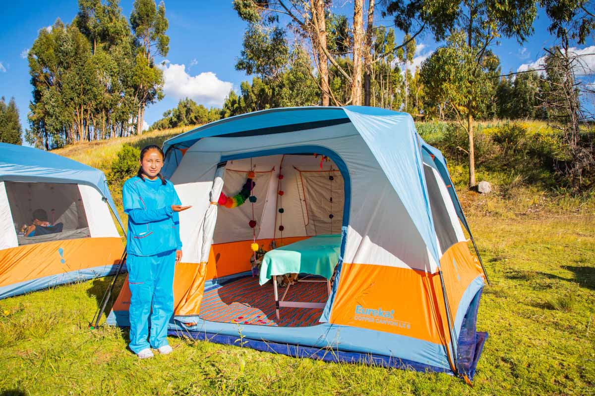 Massage shop in the middle of nature Blue and orange tent with open entrance, set up on green grass and surrounded by trees | TreXperience