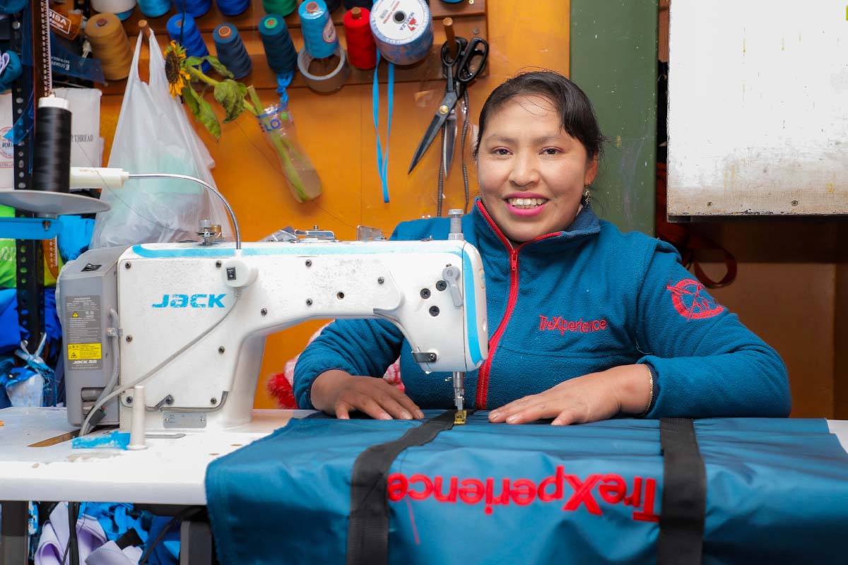 Trabajadora en TreXperience con tejidos coloridos sobre una mesa Mujer trabajando en TreXperience rodeada de materiales textiles | TreXperience