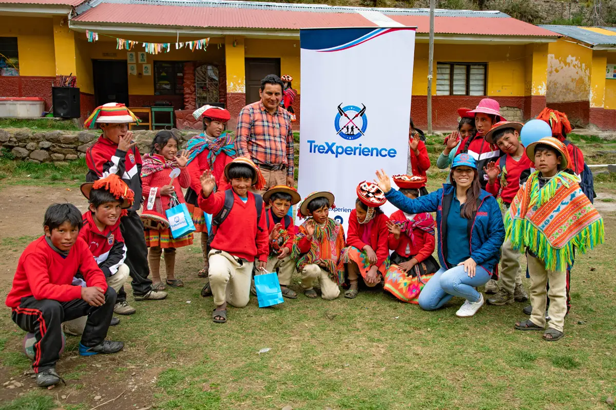 Grupo de niños y adultos posa al aire libre junto a un banner de la Campaña de cuidado dental de TreXperience, varios con vestimenta tradicional Grupo de niños y adultos posa al aire libre junto a un banner de la Campaña de cuidado dental de TreXperience, varios con vestimenta tradicional | TreXperience