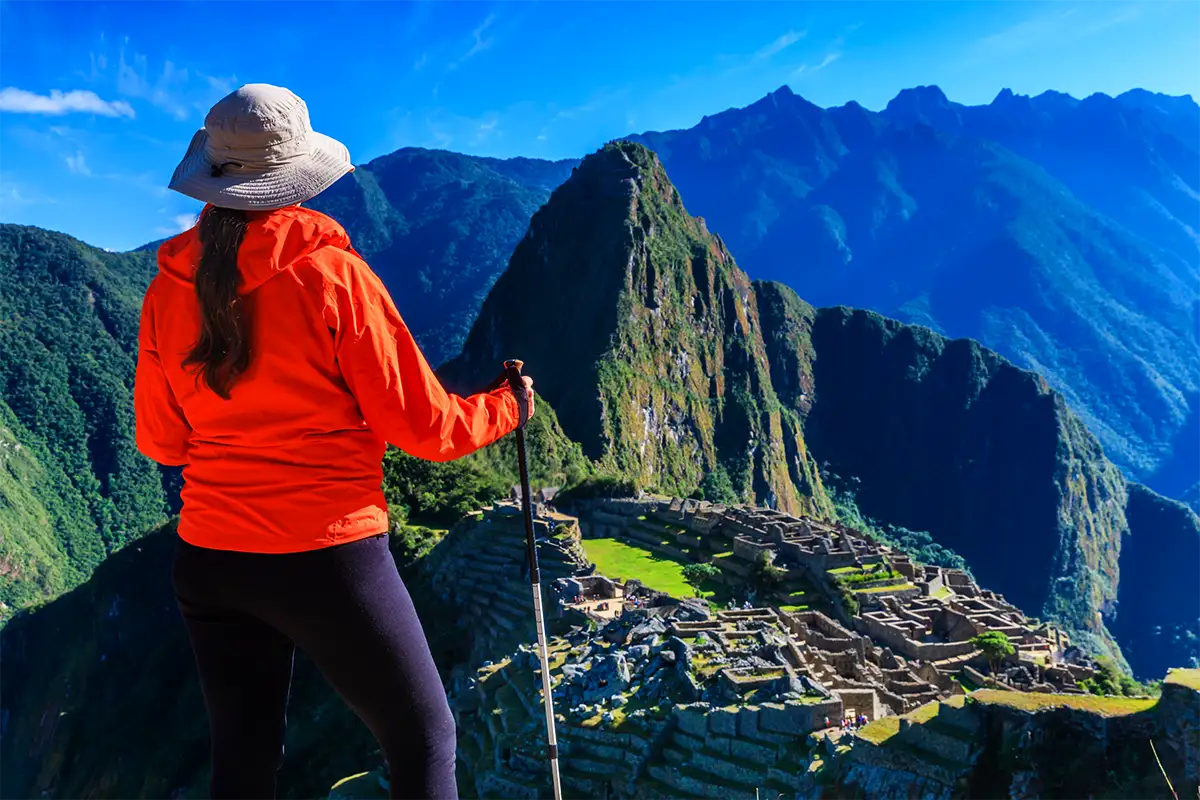 A woman with trekking poles looking at Machu Picchu | TreXperience A woman with trekking poles looking at Machu Picchu | TreXperience