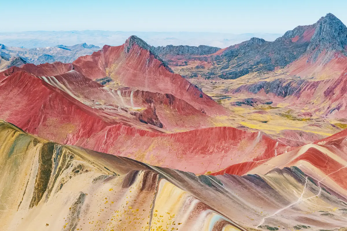 Drone View of Rainbow Mountain and Red Valley Drone view of Rainbow Mountain with the Red Valley stretching behind, highlighting vivid Andean colors and terrain.