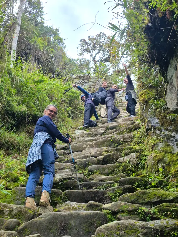 Viajeros subiendo escalinatas de piedra del Camino Inca rodeados de vegetación | TreXperience