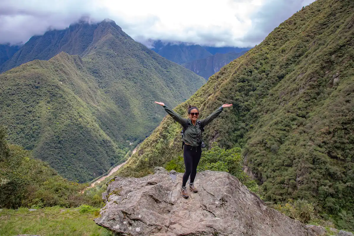 Viajera posando sobre una roca con montañas del Camino Inca corto al fondo | TreXperience