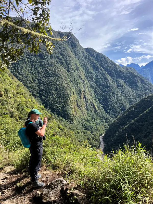 Viajera fotografiando el paisaje del Camino Inca corto con montañas y el río Urubamba al fondo | TreXperience