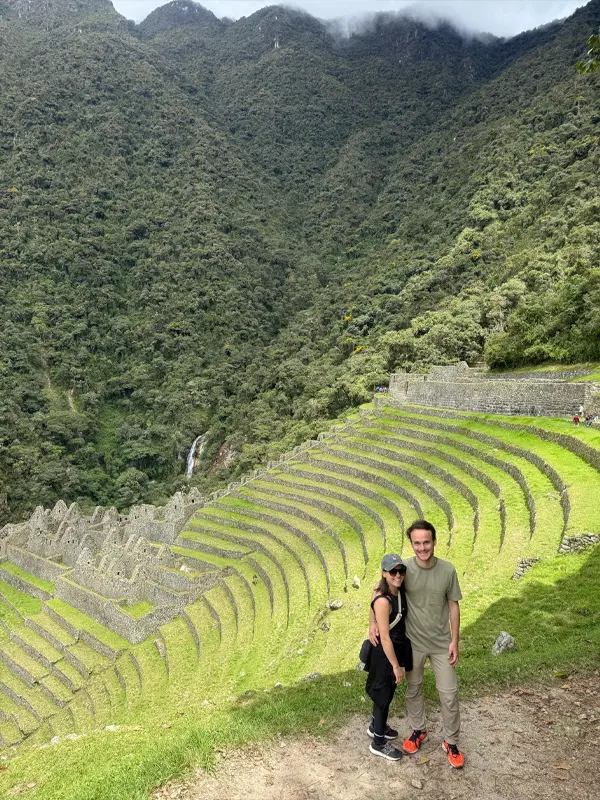 Pareja posando frente a las terrazas incas de Wiñay Wayna en el Camino Inca | TreXperience.