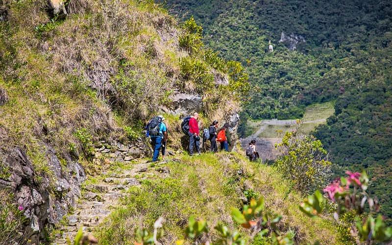 Hikers climbing the stone steps of the Short Inca Trail above Inca terraces on the way to Machu Picchu