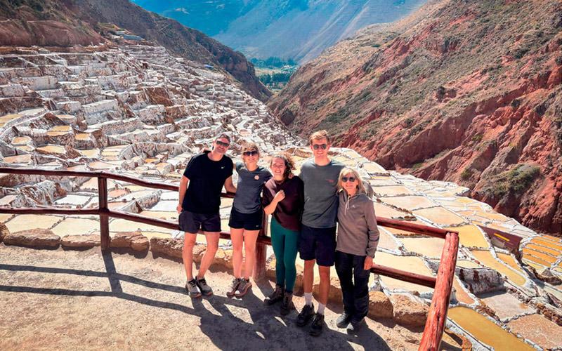 Cinco viajeros posando en un mirador de las Salineras de Maras con pozas de sal y montañas al fondo
