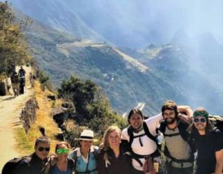 Turistas sonriendo tras haber llegado a Intipunku la entrada panoramica de Machu Picchu, parte del Camino Inca Corto Confort