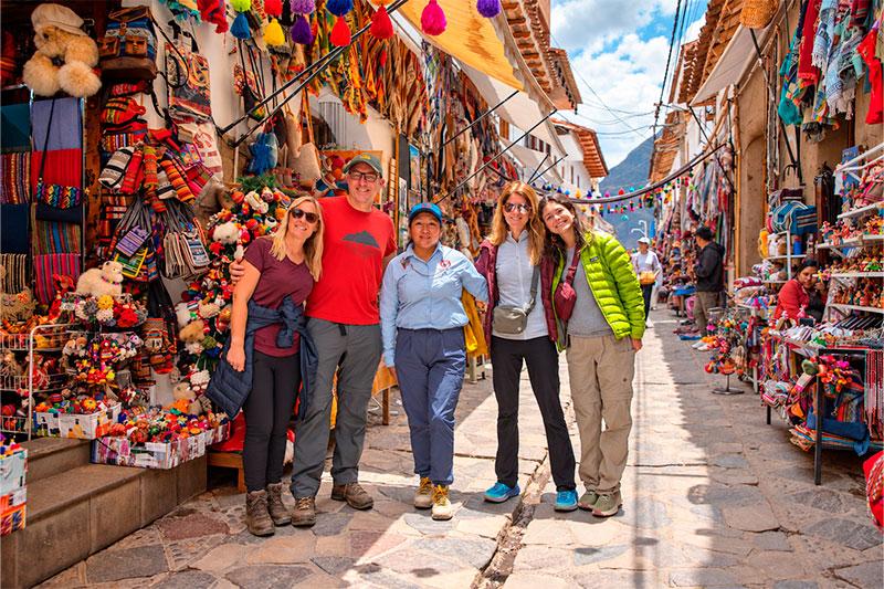 Cuatro viajeros y su guía de TreXperience entre puestos de textiles coloridos y artesanías andinas