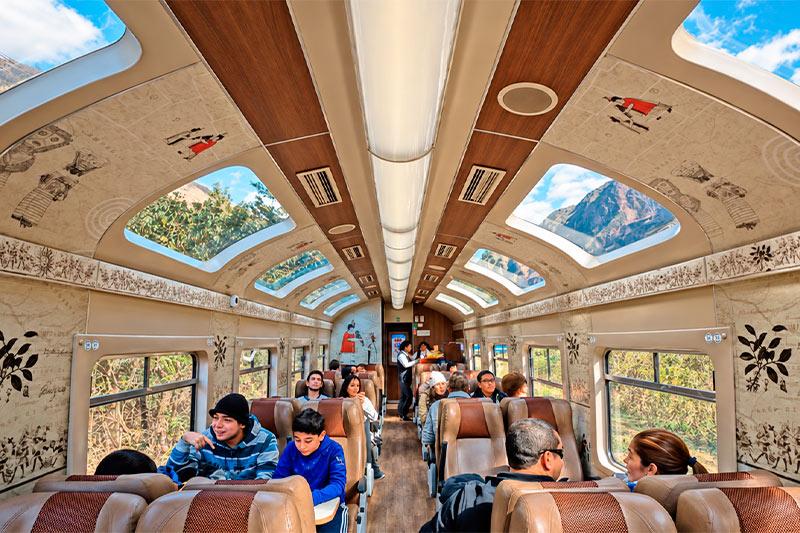Interior del tren Expedition con pasajeros sentados y vistas a las montañas por las ventanas del techo