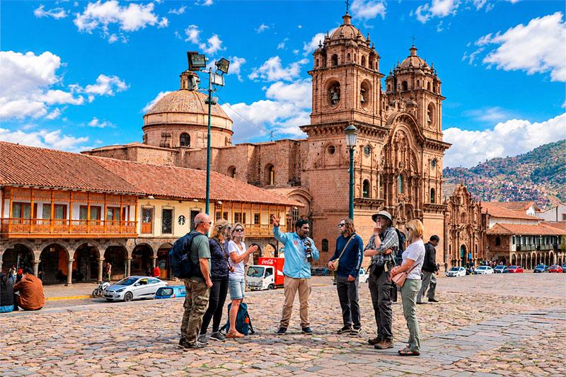Guía de TreXperience con viajeros en la Plaza de Armas de Cusco frente a la iglesia de la Compañía de Jesús