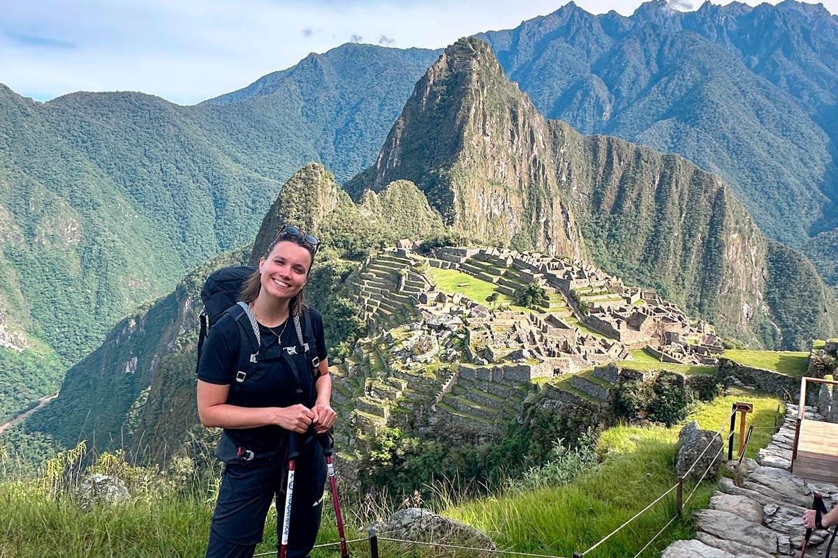 Traveler with backpack and hiking poles posing in front of Machu Picchu during a hike | TreXperience