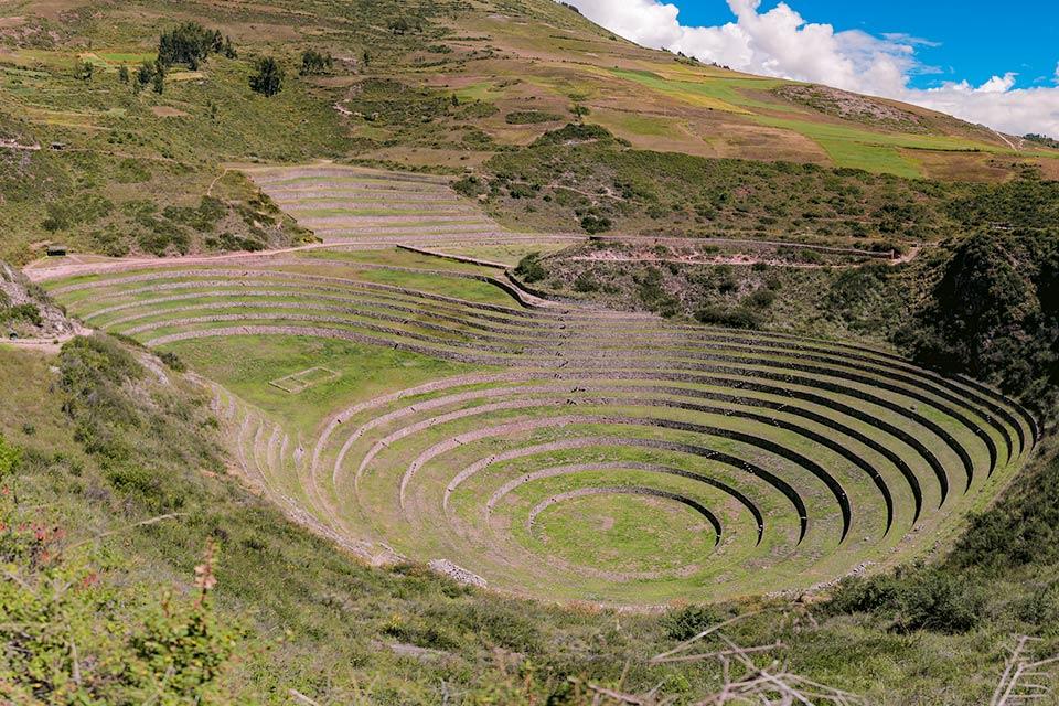 Vista de terrazas circulares de piedra en Moray rodeado de laderas verdes | TreXperience