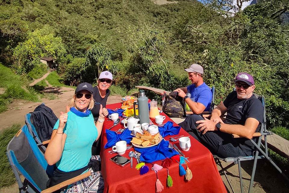 Grupo de viajeros sentados en una mesa con comida servida durante el Camino Inca corto | TreXperience