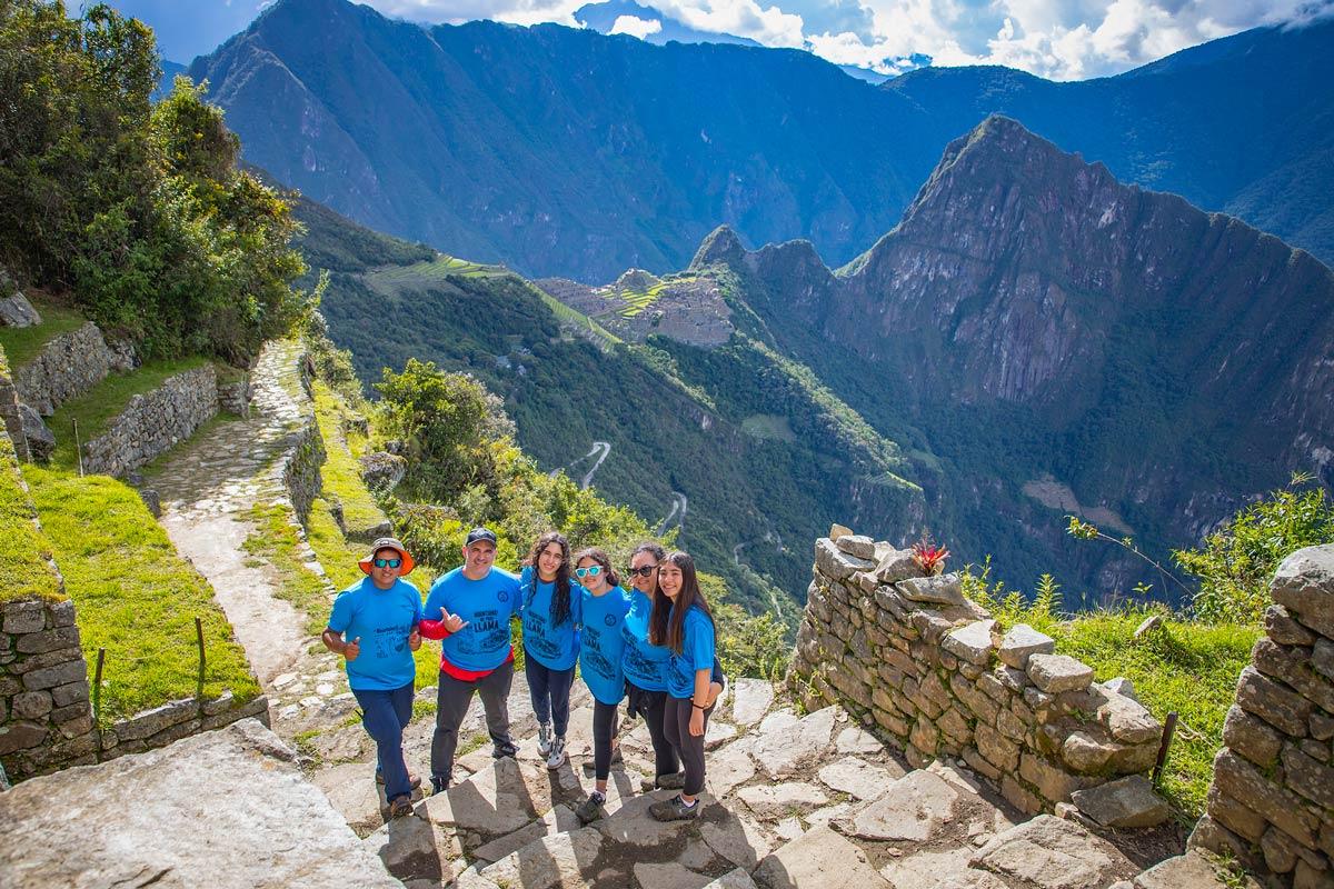 Group of travelers posing with a panoramic view of Machu Picchu during a hike | TreXperience