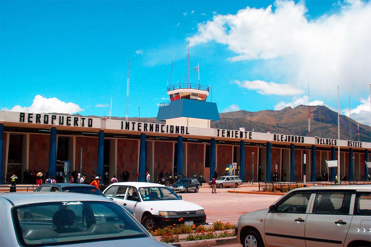 Fachada del Aeropuerto Internacional Teniente Alejandro Velasco Astete con autos y montañas al fondo | TreXperience