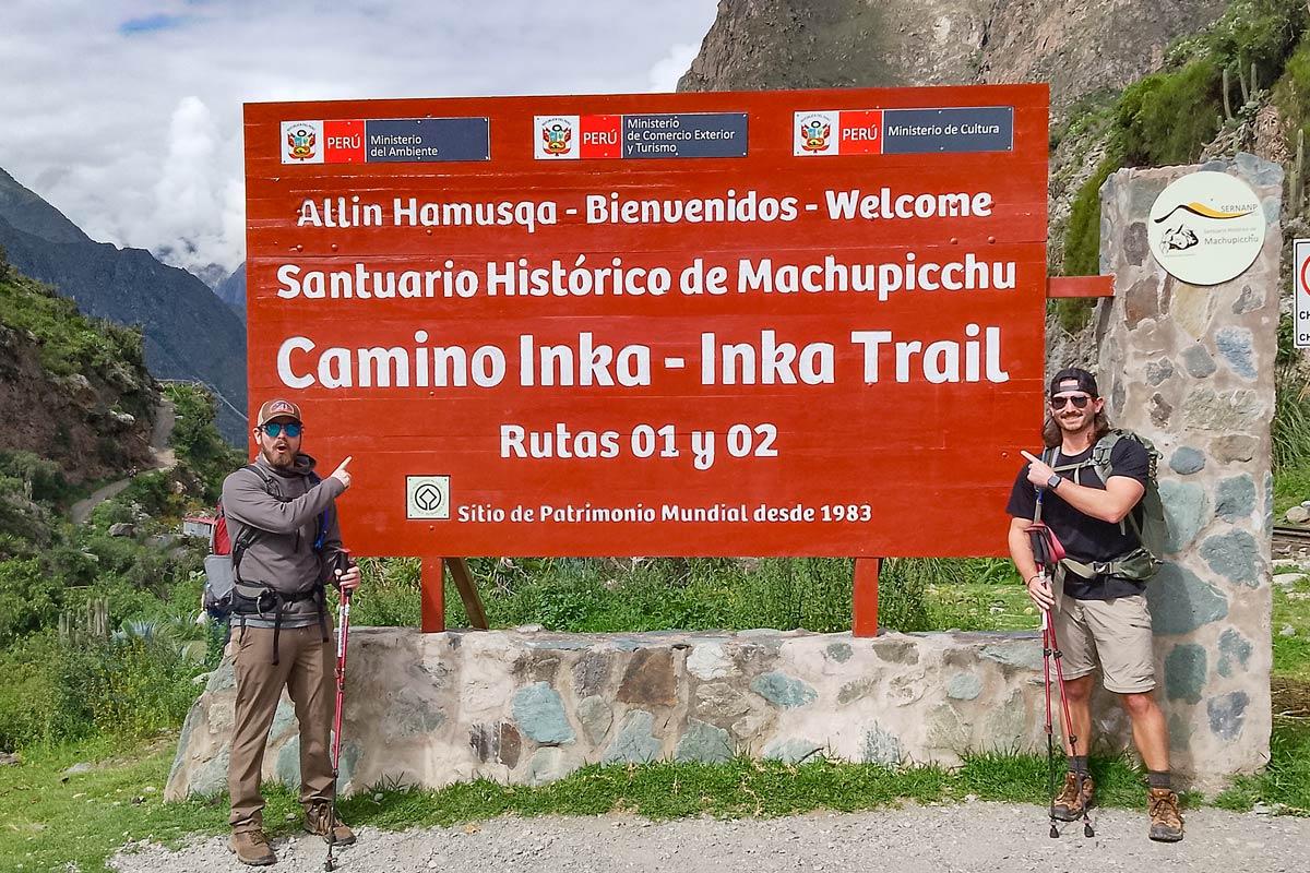 Dos viajeros posando junto al letrero del Camino Inca hacia Machu Picchu | TreXperience