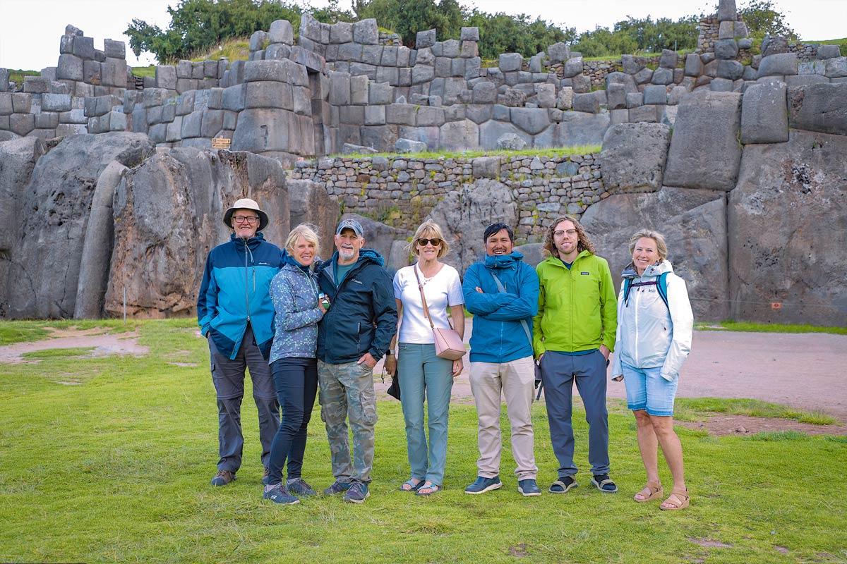 Group of travelers posing in front of stone walls at Sacsayhuaman | TreXperience