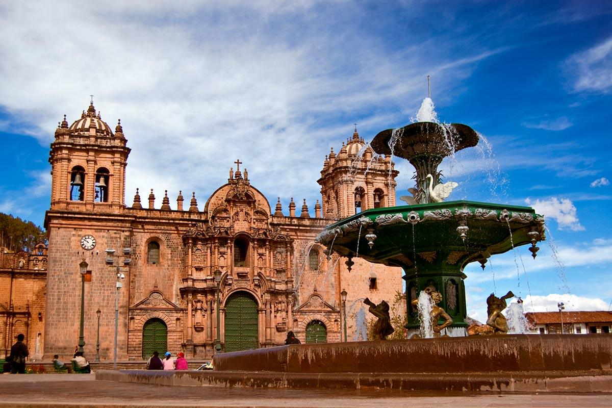 Catedral de piedra y fuente en una plaza con cielo azul y nubes | TreXperience