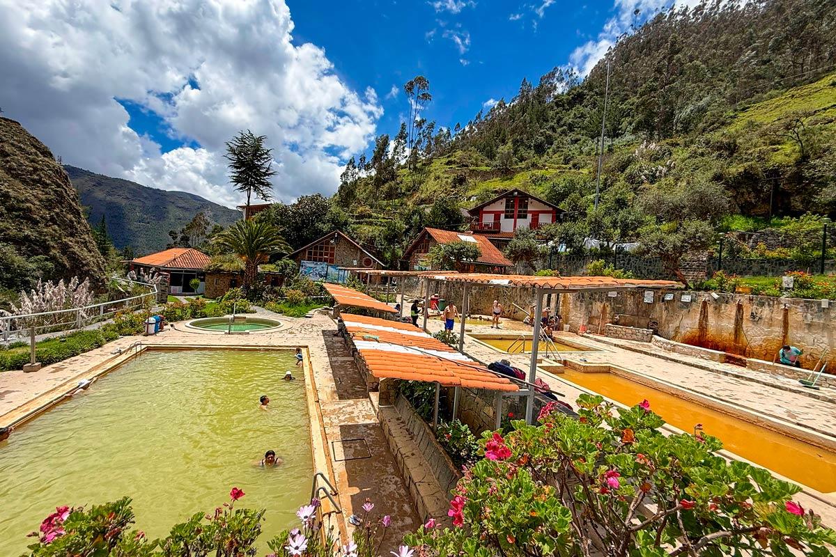 Panoramic view of outdoor thermal pools with visitors surrounded by a mountain landscape and Andean vegetation | TreXperience