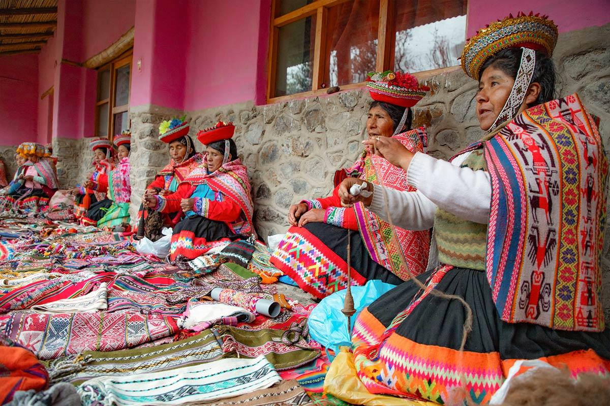 Group of people making textiles with traditional Andean clothing at a handicrafts market | TreXperience