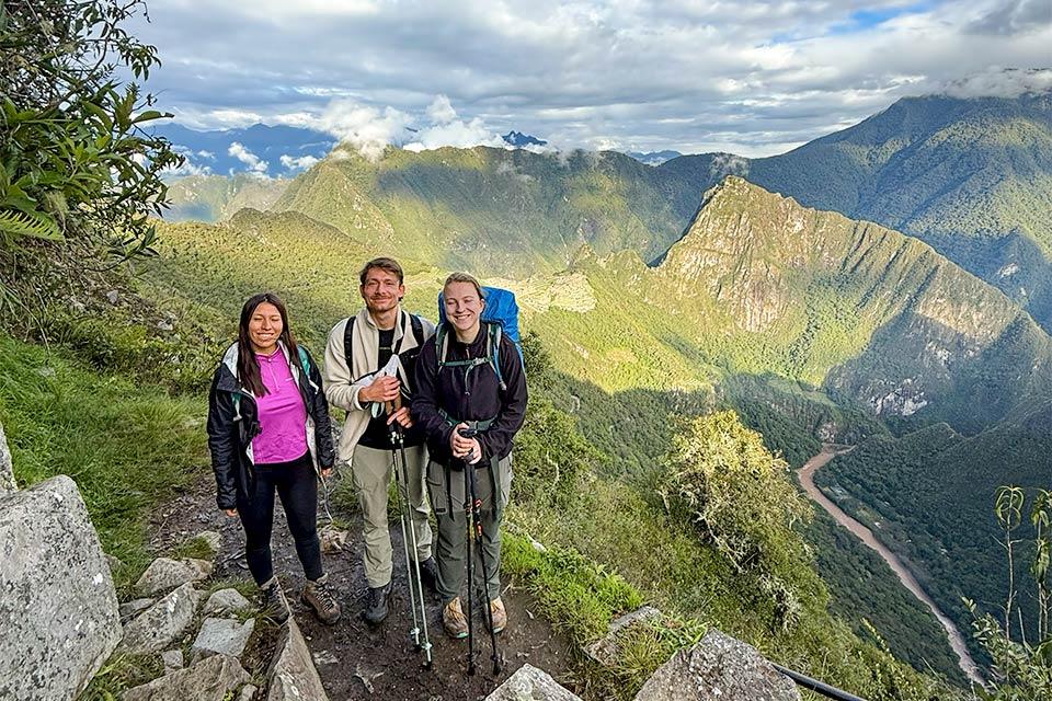 Hiker group posing at an Inca Trail viewpoint with mountains and a river in the background (2-day Inca Trail camping) | TreXperience