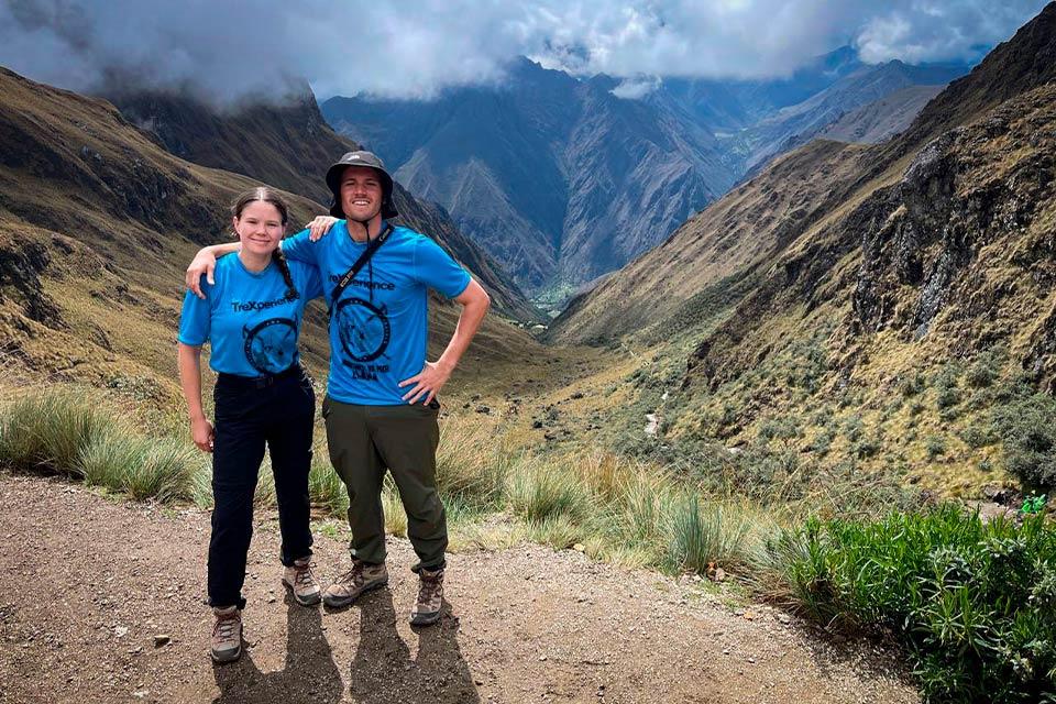 Pareja de senderistas posando en un paso de montaña con valle andino y nubes al fondo (Camino Inca 5 días, versión extendida) | TreXperience