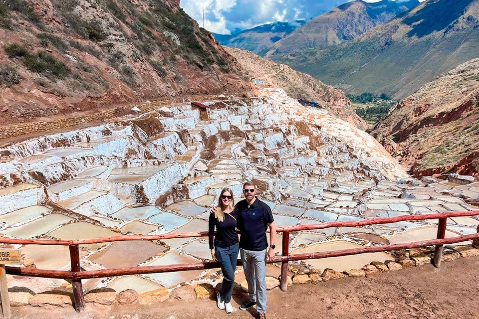Traveler couple posing with a panoramic view of the Maras Salt Mines (Maras, Moray & Chinchero half-day tour) | TreXperienc