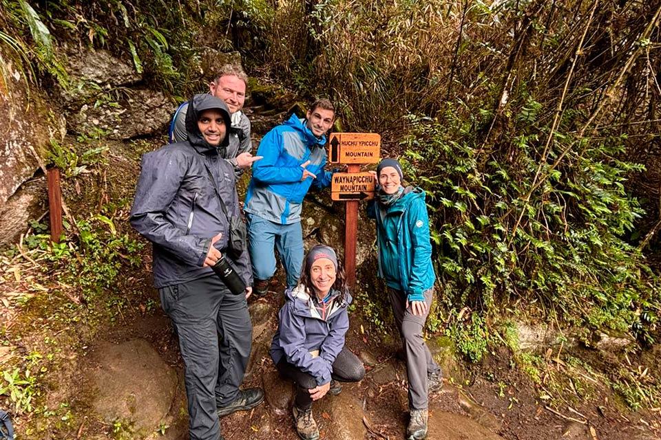 Grupo de viajeros junto al letrero de desvío a Huayna Picchu y Huchuy Picchu en Machu Picchu (Tour privado del Camino Inca 4 días) | TreXperience