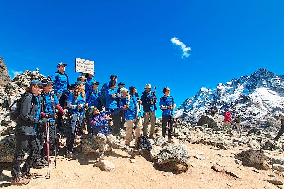 Grupo de caminantes posa junto al letrero Abra Salkantay con montañas nevadas al fondo, Caminata Salkantay y Laguna Humantay 2 días | TreXperience