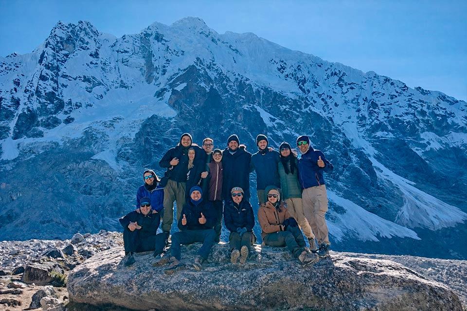 Group of hikers poses on a large rock with Nevado Salkantay in the background, Salkantay Trek 4 Days to Machu Picchu | TreXperience