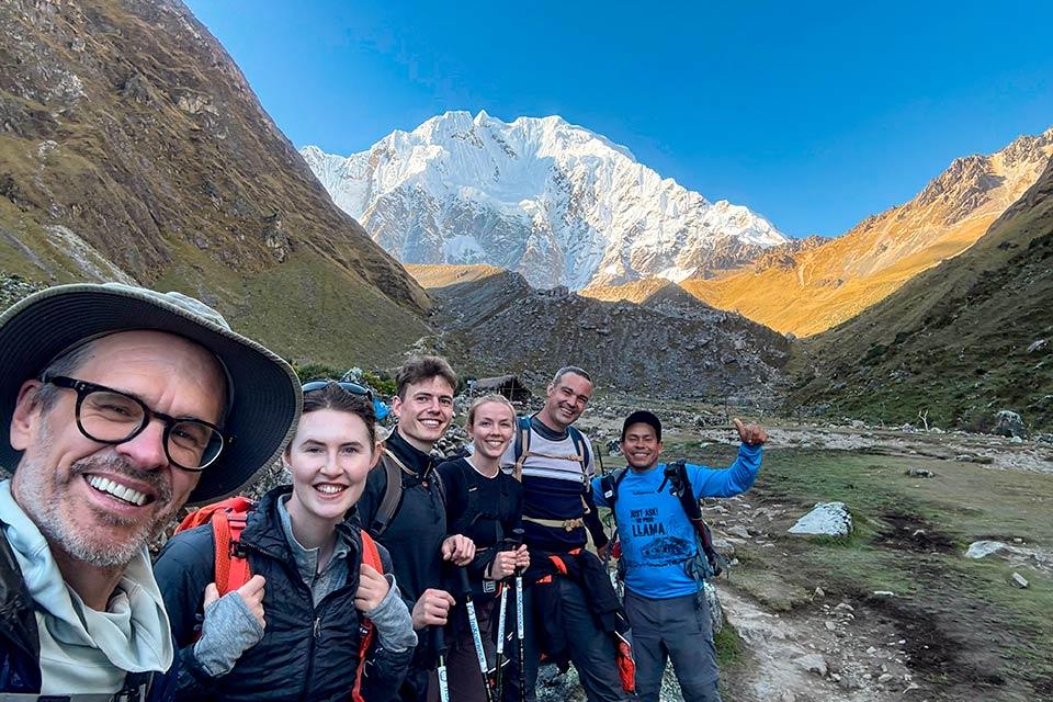 Group of hikers smiles for a photo with Nevado Salkantay in the background in a mountain valley, Salkantay Trek 4 Days to Machu Picchu | TreXperience