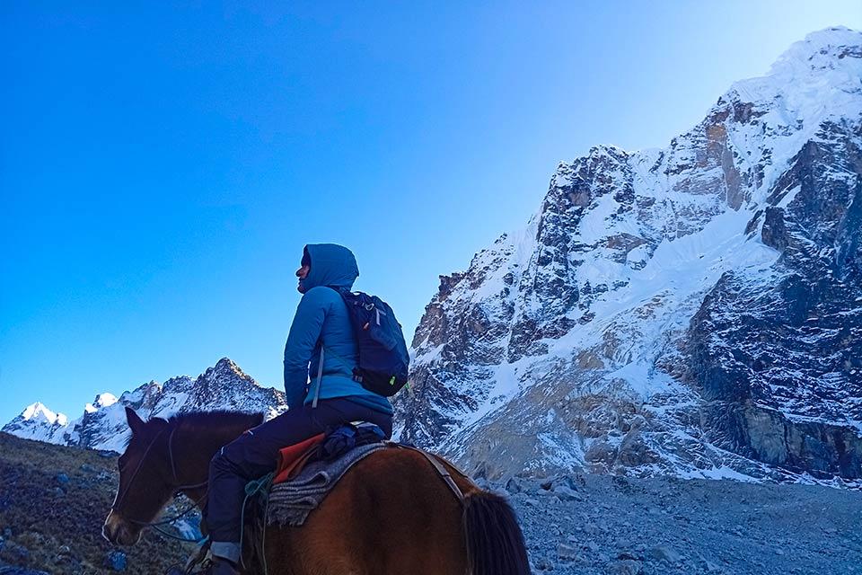 Person on horseback in front of Nevado Salkantay and a rocky wall under a blue sky, Salkantay Trek 5 Days to Machu Picchu | TreXperience
