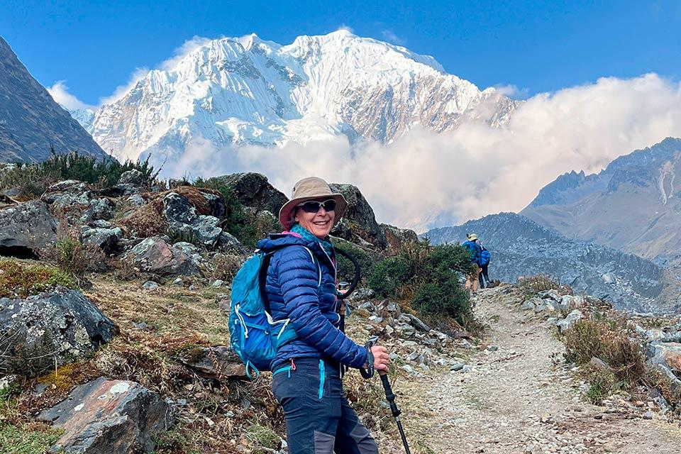 Smiling hiker with a trekking pole and backpack on a mountain trail with Nevado Salkantay behind, Salkantay Trek 5 Days to Machu Picchu | TreXperience