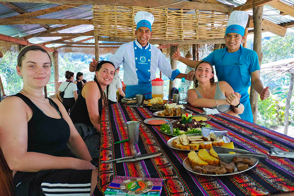 Outdoor lunch with a set table, guests, and cooks in blue uniforms in a rustic dining area, Salkantay Trek 5 Days to Machu Picchu | TreXperience
