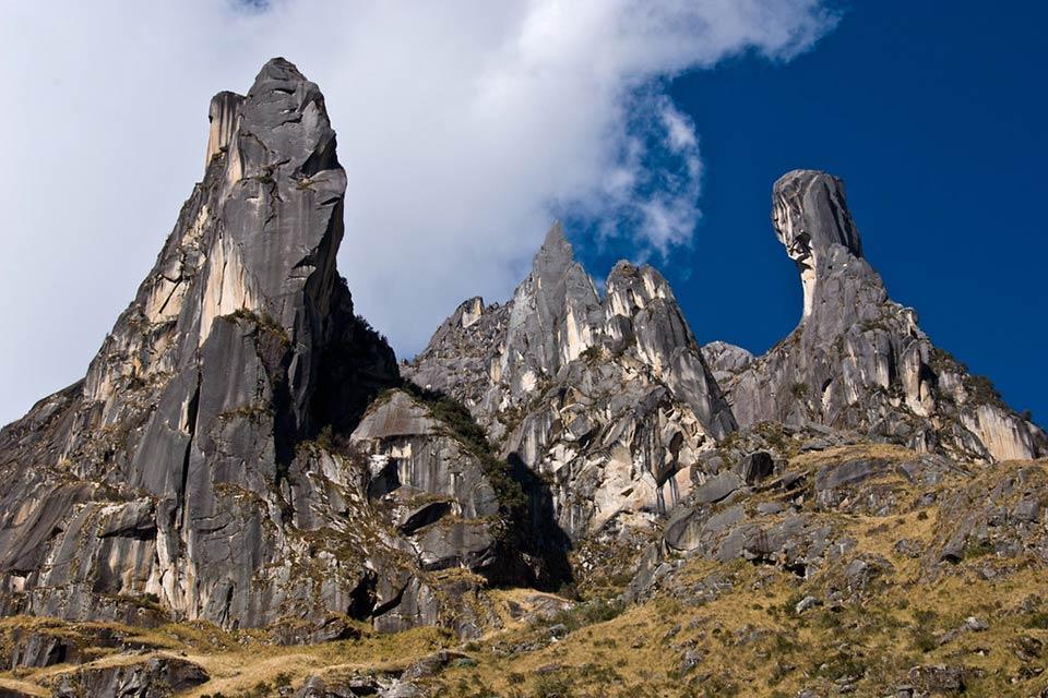 Tall dark rock formations at the Ccaccahuara Stone Forest under a blue sky with clouds, Cachicata Inca Quarry Trek to Machu Picchu 4 Days 3 Nights | TreXperience