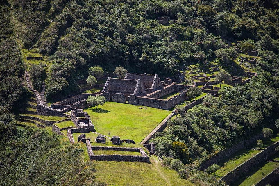 Wide view of Choquequirao stone terraces and enclosures around a large green plaza, Choquequirao Trek to Machu Picchu 6 Days | TreXperience