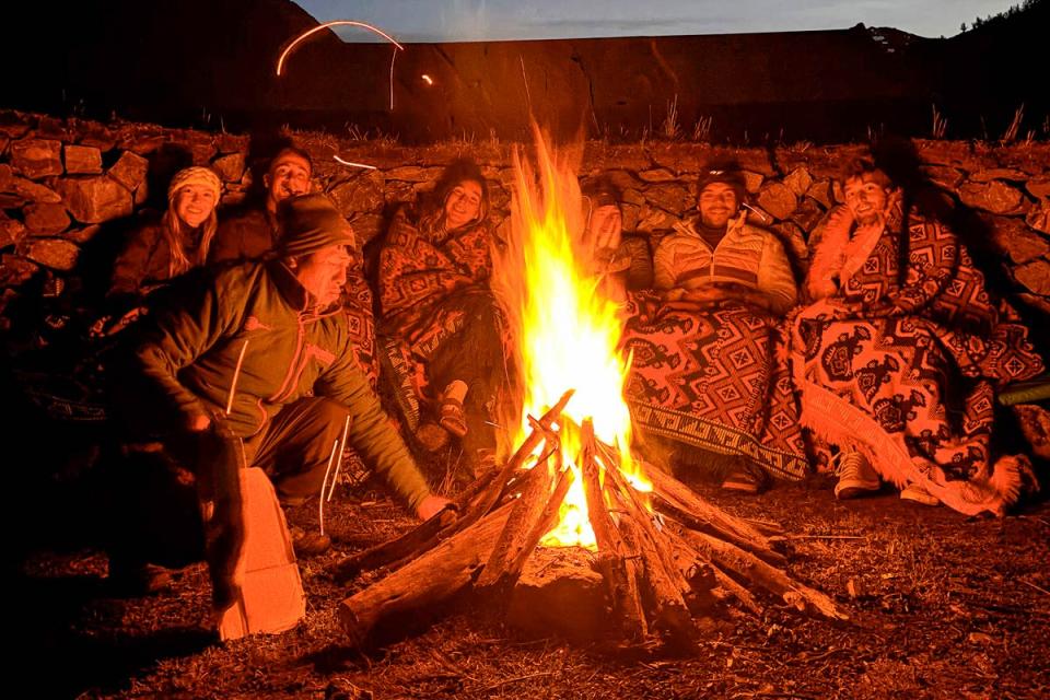 Grupo de viajeros en la noche compartiendo una fogata | TreXperience