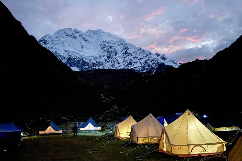 Campamento Salkantay Glamping iluminado al anochecer frente a la montaña nevada | TreXperience